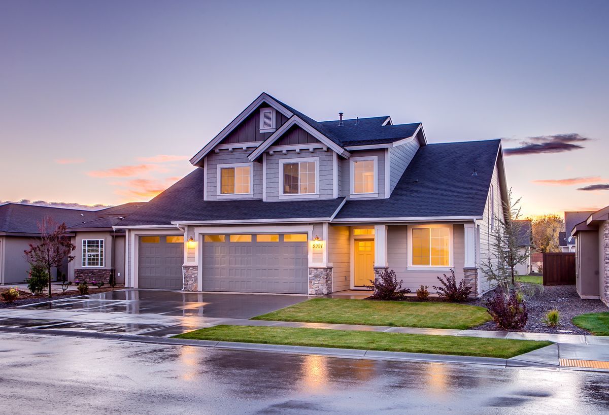 Suburban home at dusk with a clean driveway and a three-car garage