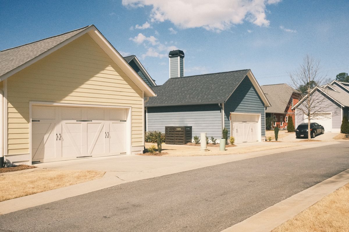 Suburban street of single-story homes with garages and concrete driveways under a blue sky